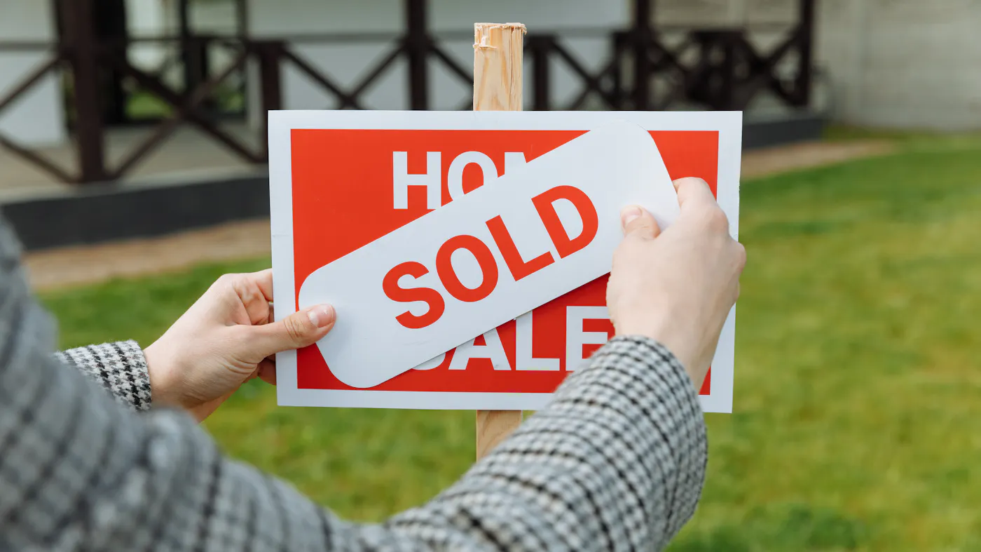 A real estate professional placing a sold sticker on a sign — a closed Texas probate house sale