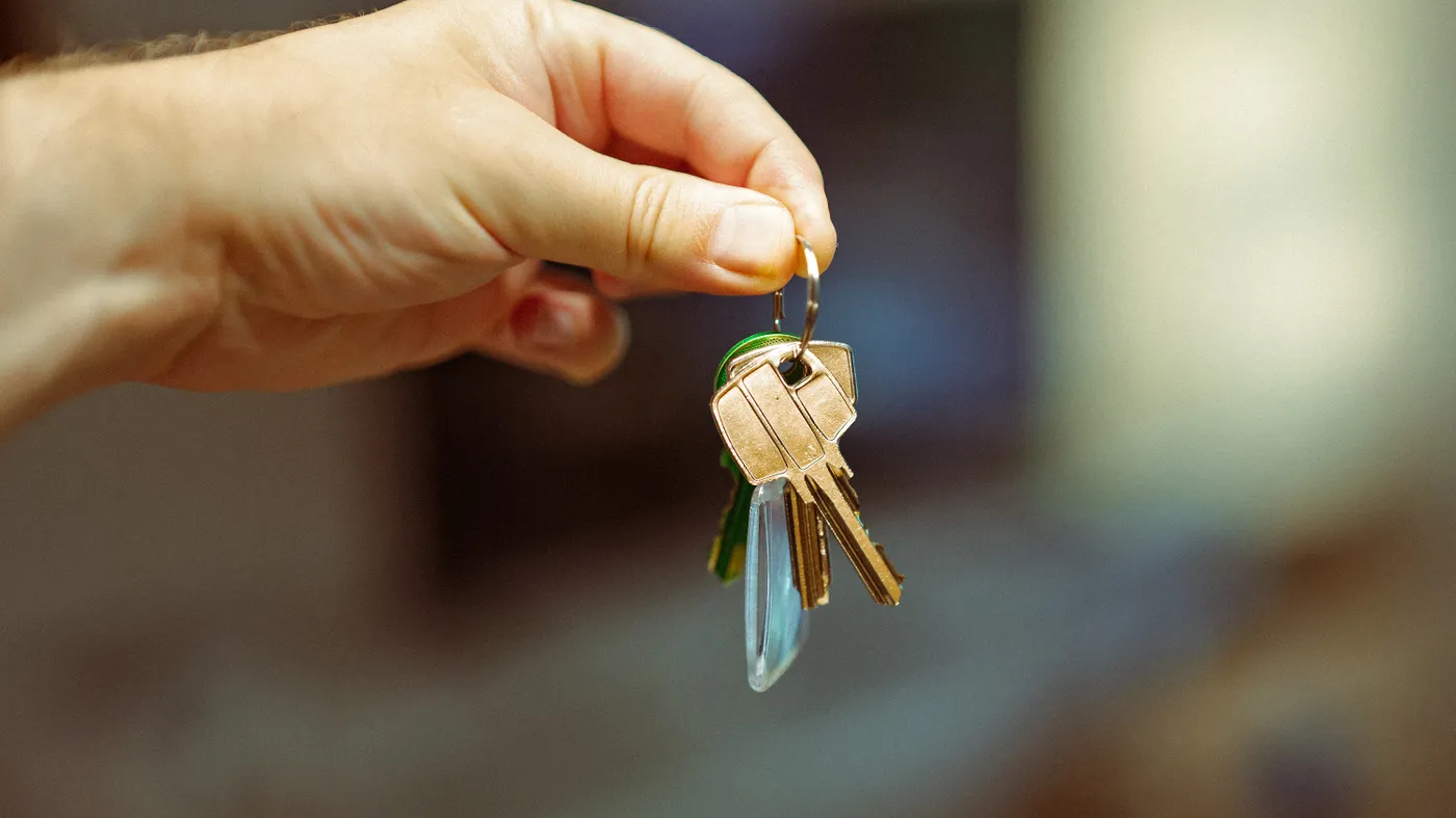A hand holding the keys to an inherited house ready to sell for cash in Texas