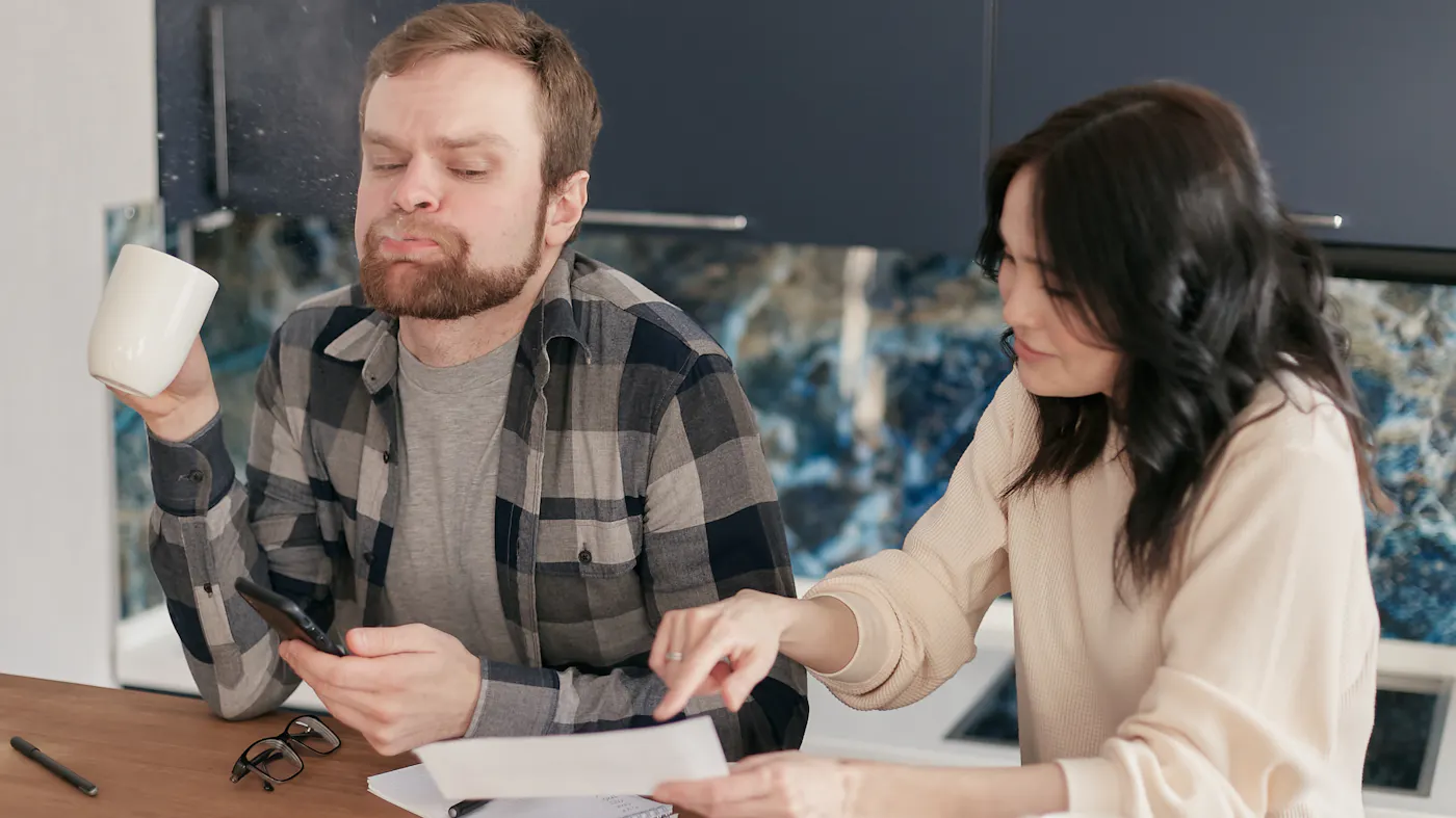 A couple reviewing financial documents at their kitchen table while deciding whether to sell their home quick